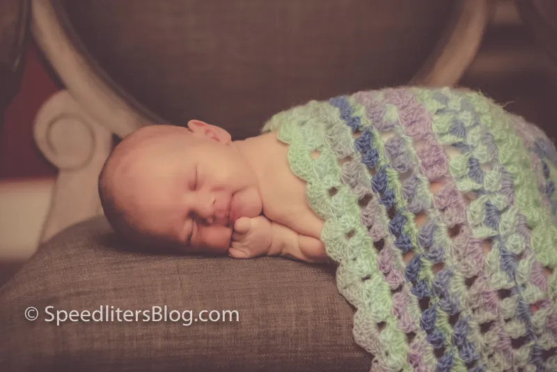 Close-up of a sleeping newborn under a crocheted blanket
